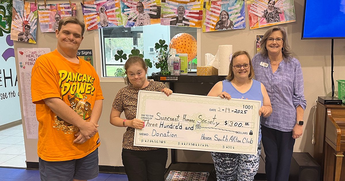 Christine Varcoe from Suncoast Humane Society stands beside three young people holding an oversized check made out to the Humane Society